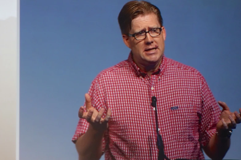 a man in a red checkered shirt has his hands out and holds his hands out