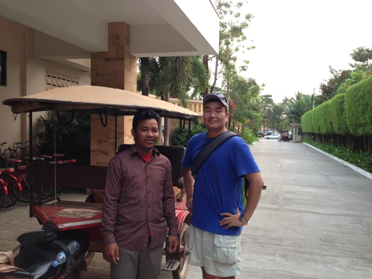 two men are standing next to an old style cart