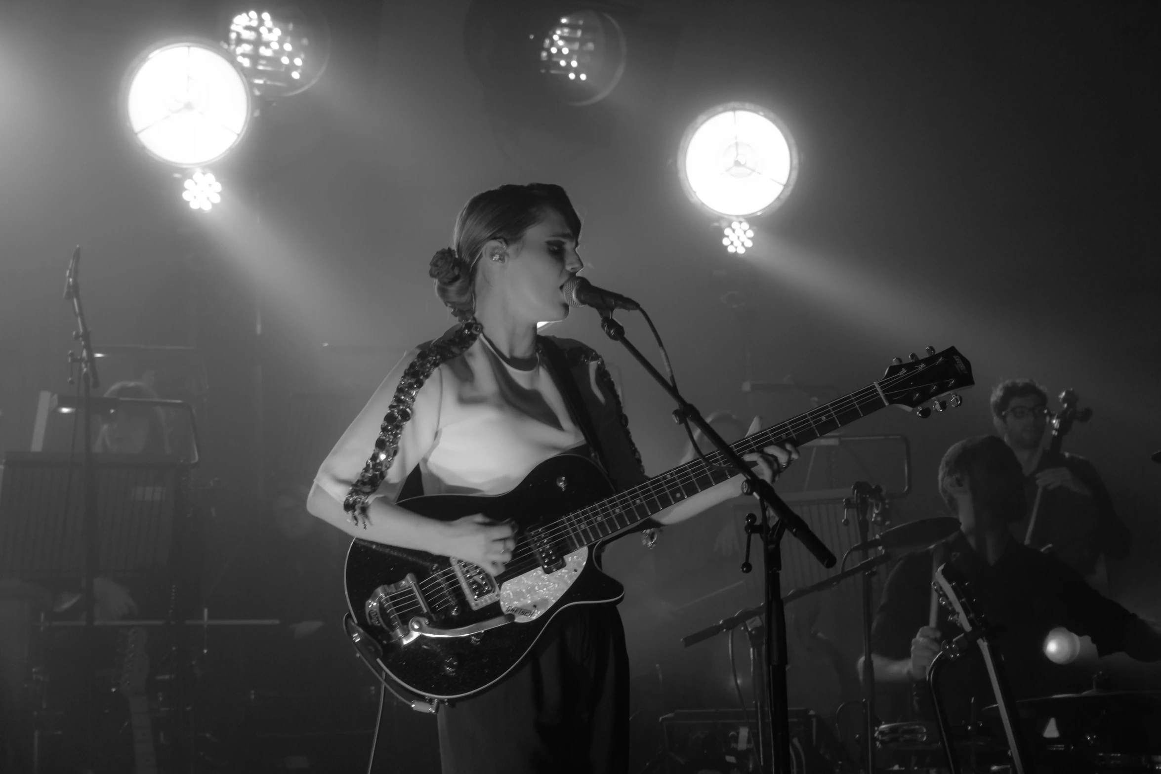 woman on stage singing into microphone with bass