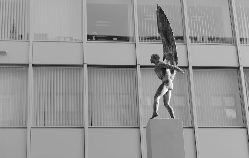 an artful sculpture holding an object in front of a building