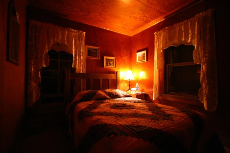 a el bedroom with a nice bed, window curtains, and a lamp