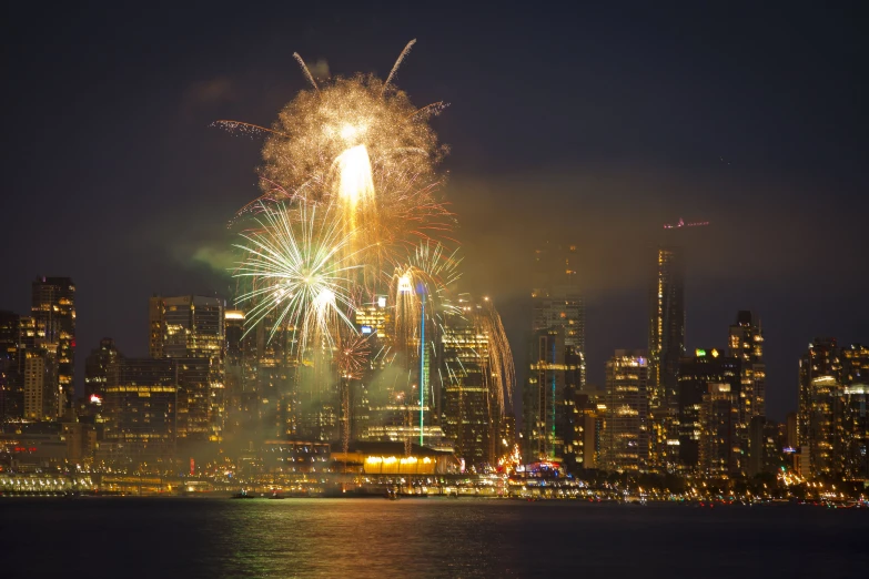 fireworks at night in a city bay area with tall buildings