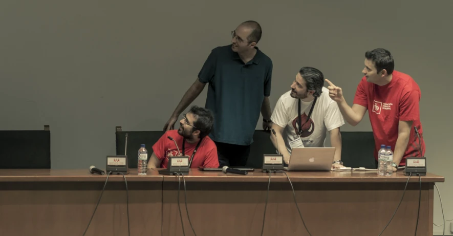 people in front of a table with laptops and speakers