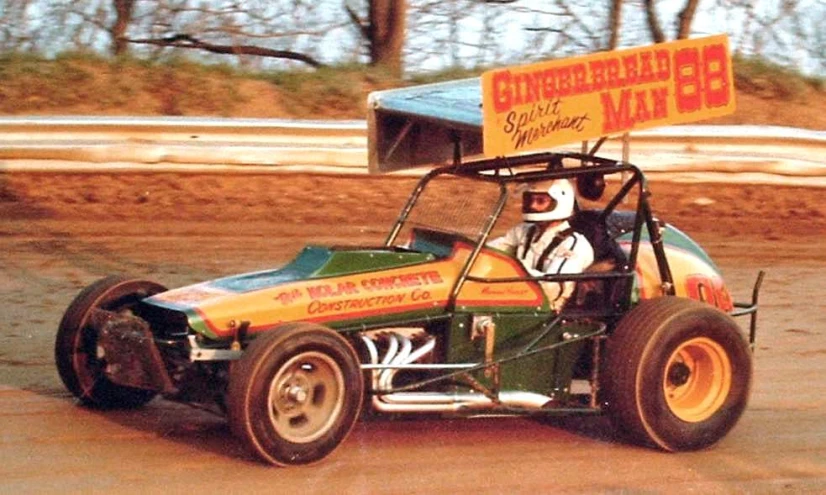 a man riding a green and yellow race car with a man inside