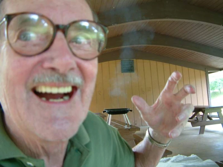 an older man smiling while smoking on his cigarette