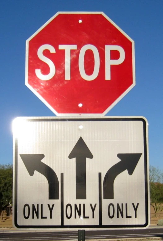 a red stop sign above a white one way street sign