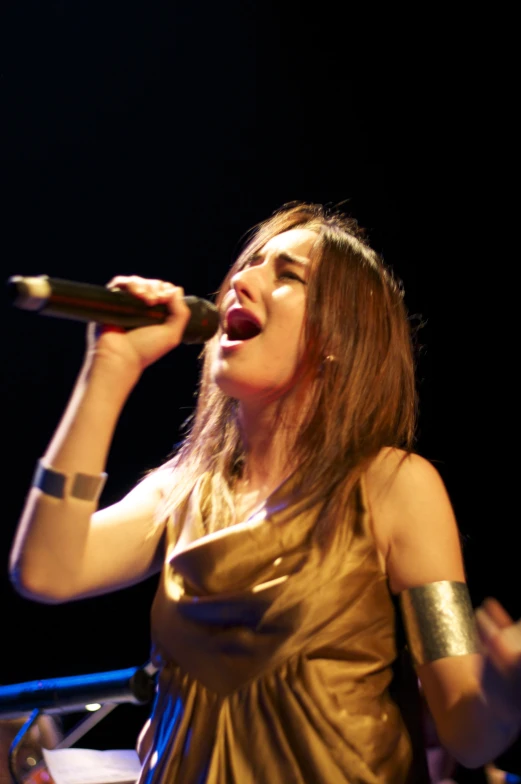 a woman singing into a microphone on stage