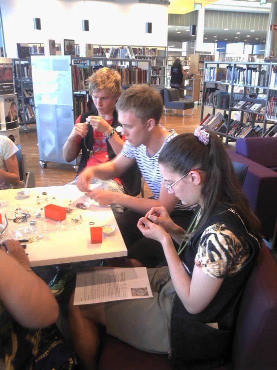 four young people sit at a liry reading