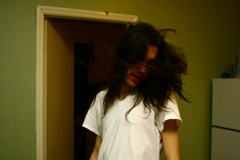 a man with long hair standing in a room