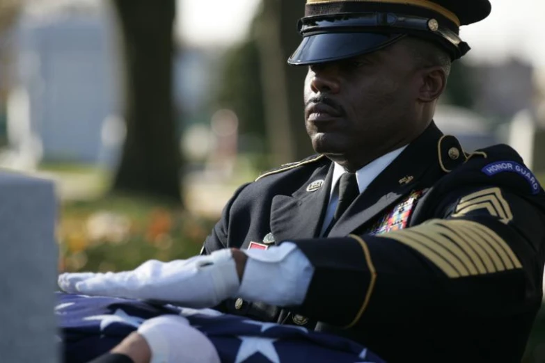 a military person sits beside a folded american flag