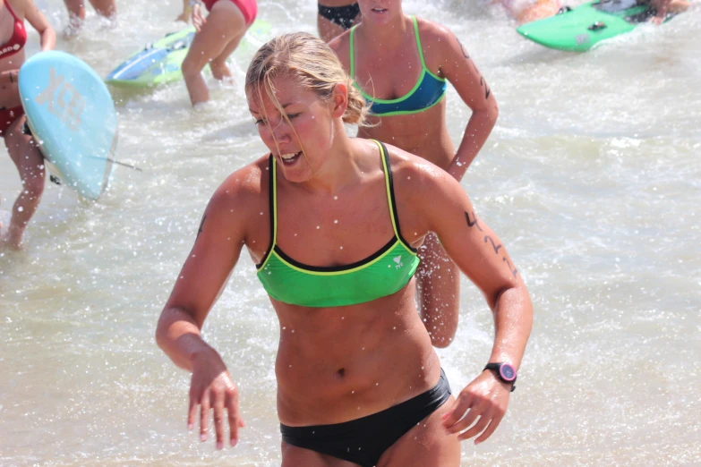 a woman in bikini running into the ocean on a surfboard