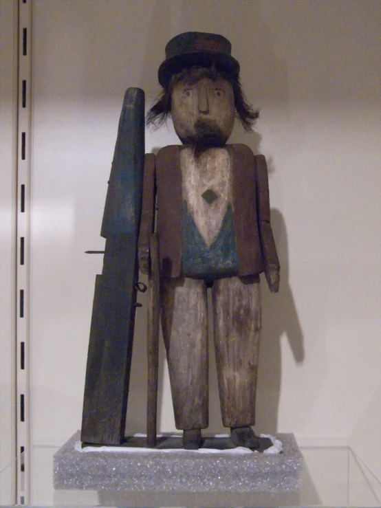 a small wooden statue wearing a hat and carrying a knife