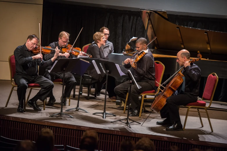 string orchestra on stage with musicians and conductor