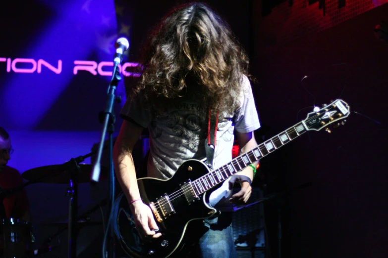 man with long hair playing an electric guitar