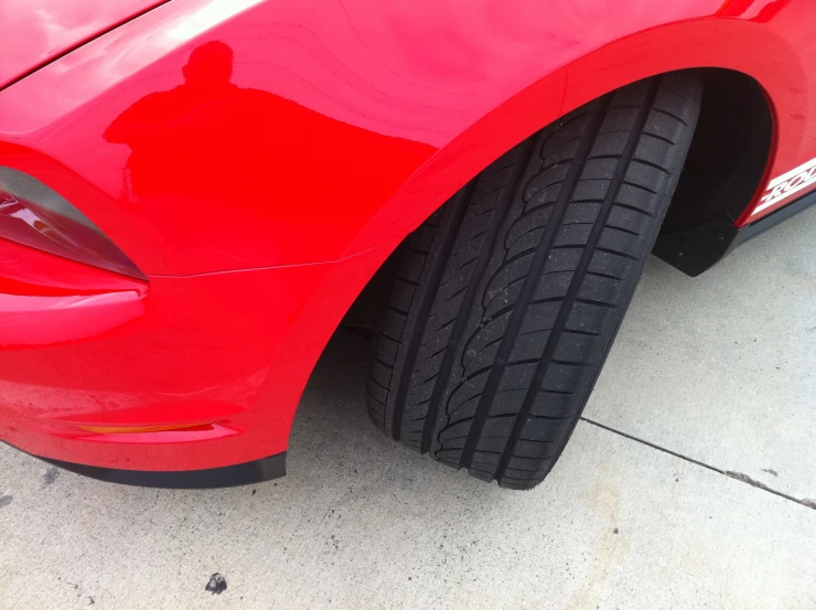 the fender of a red sports car parked on the sidewalk