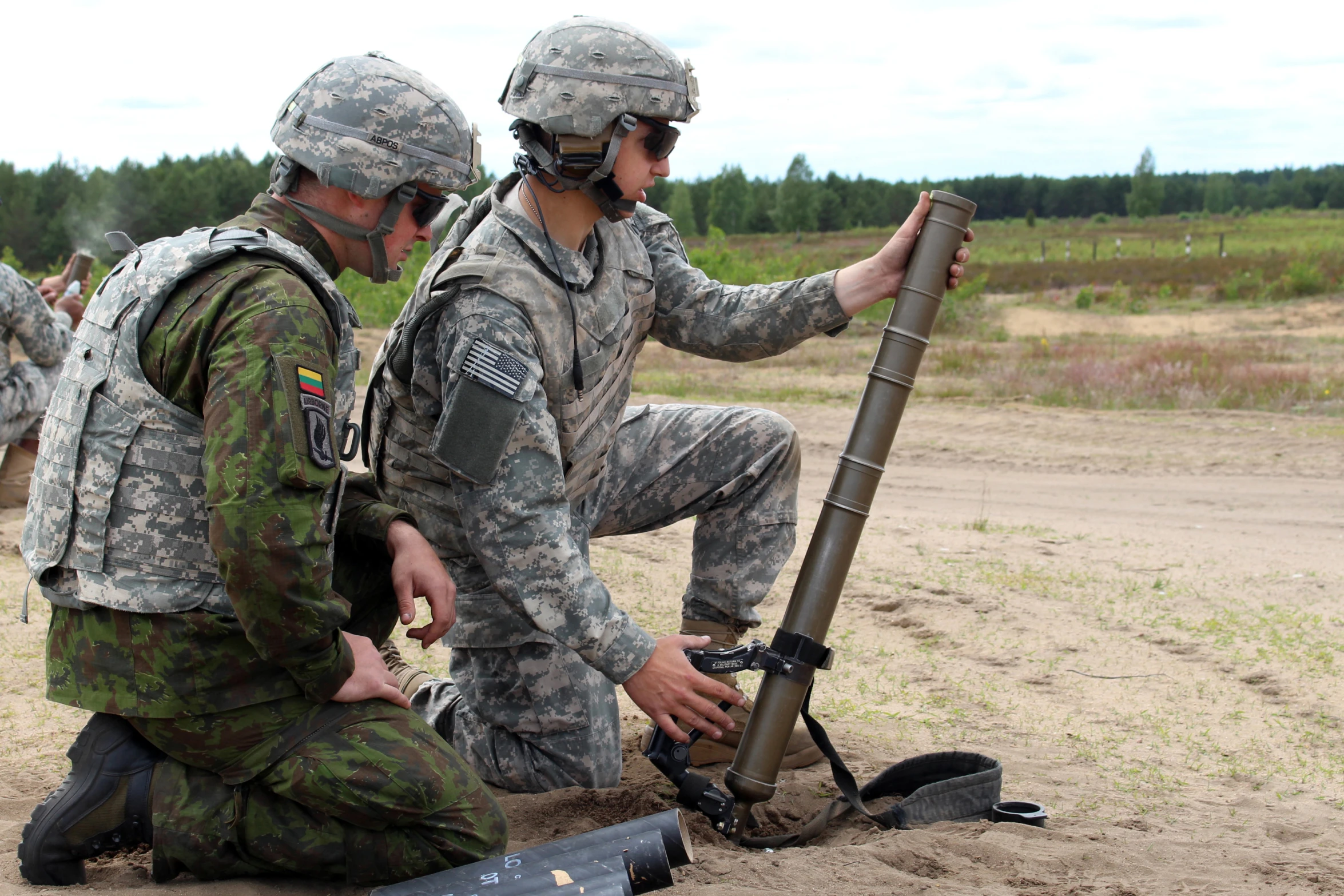 two soldiers prepare to put their weapon into an object