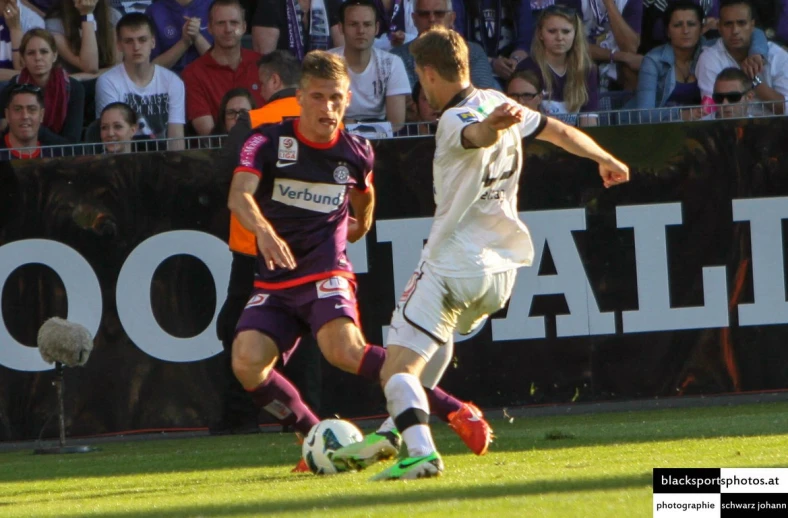 two soccer players chase after a ball on the field