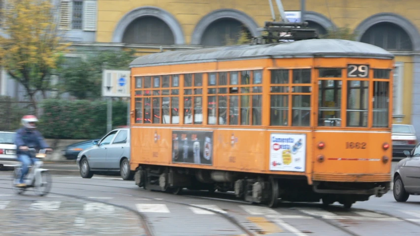 a trolley car travelling on the road next to a cyclist