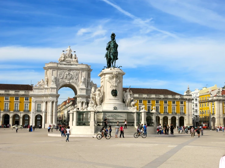 people walking in a plaza and walking past a statue