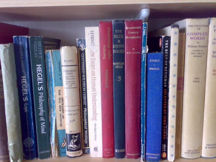 several books sitting on a shelf and one is red, yellow, blue and white