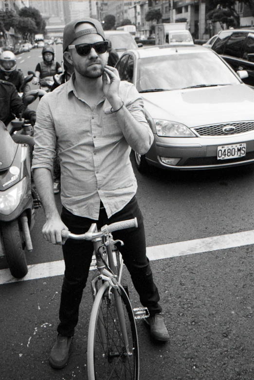 man on bike talking on cell phone while standing next to sidewalk