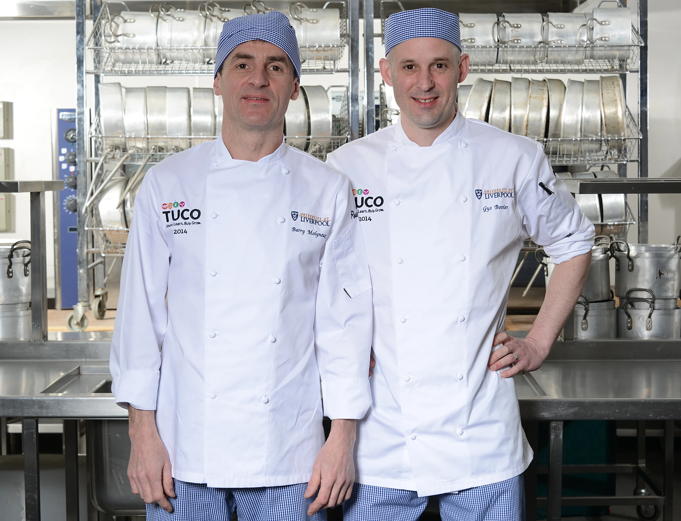 two chefs standing in front of metal equipment