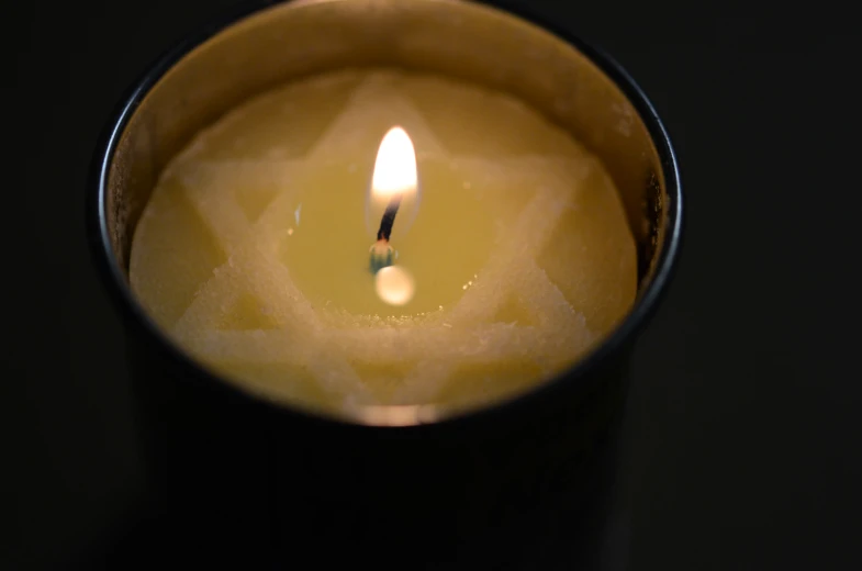 a lit candle is reflected in the glass