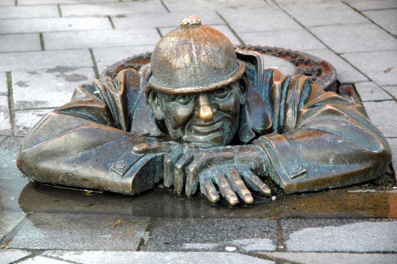 a bronze statue of a man laying on a brick walkway
