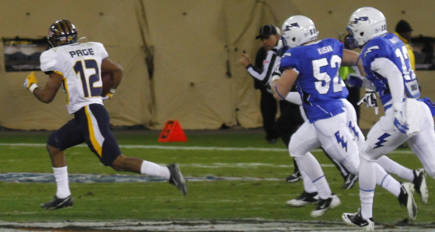 a football player runs the ball with the other team behind him