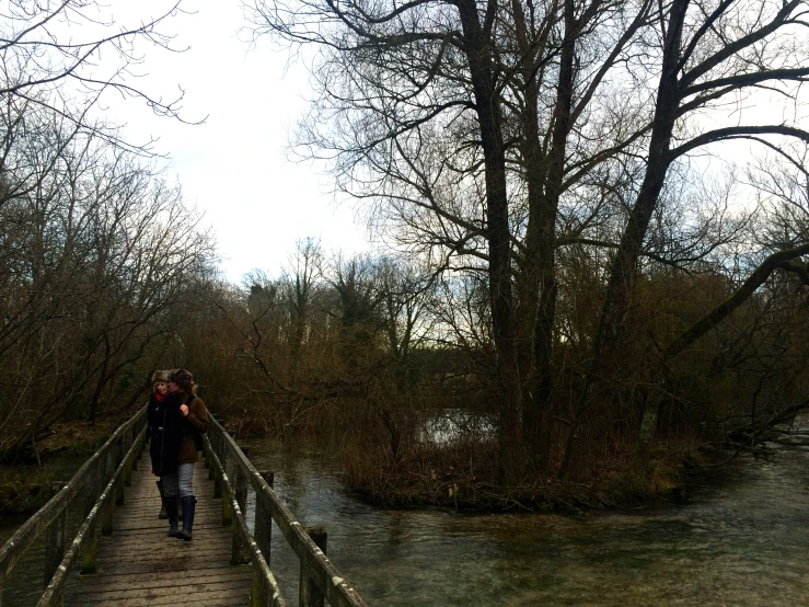 two people walk down a bridge over a river