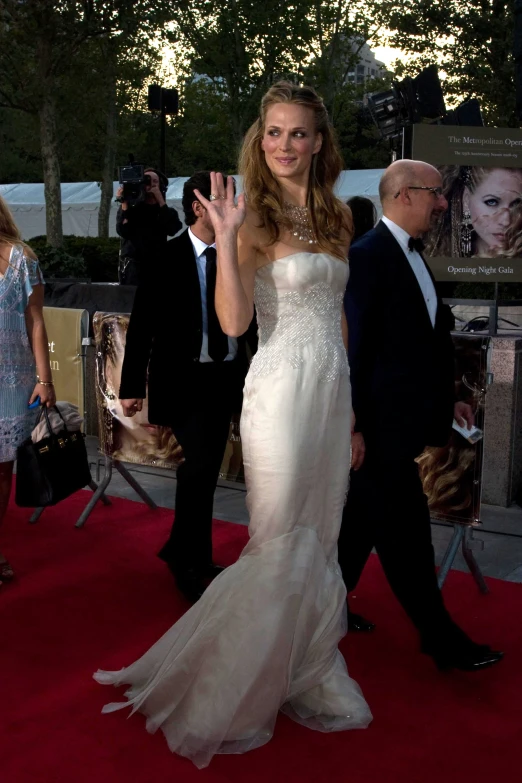 a lady in white dress walking on a red carpet