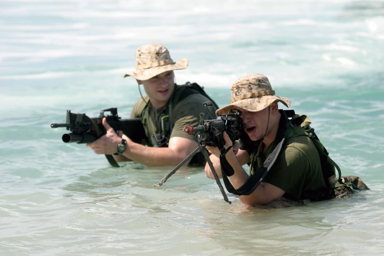 two people wearing hats and holding cameras near the beach