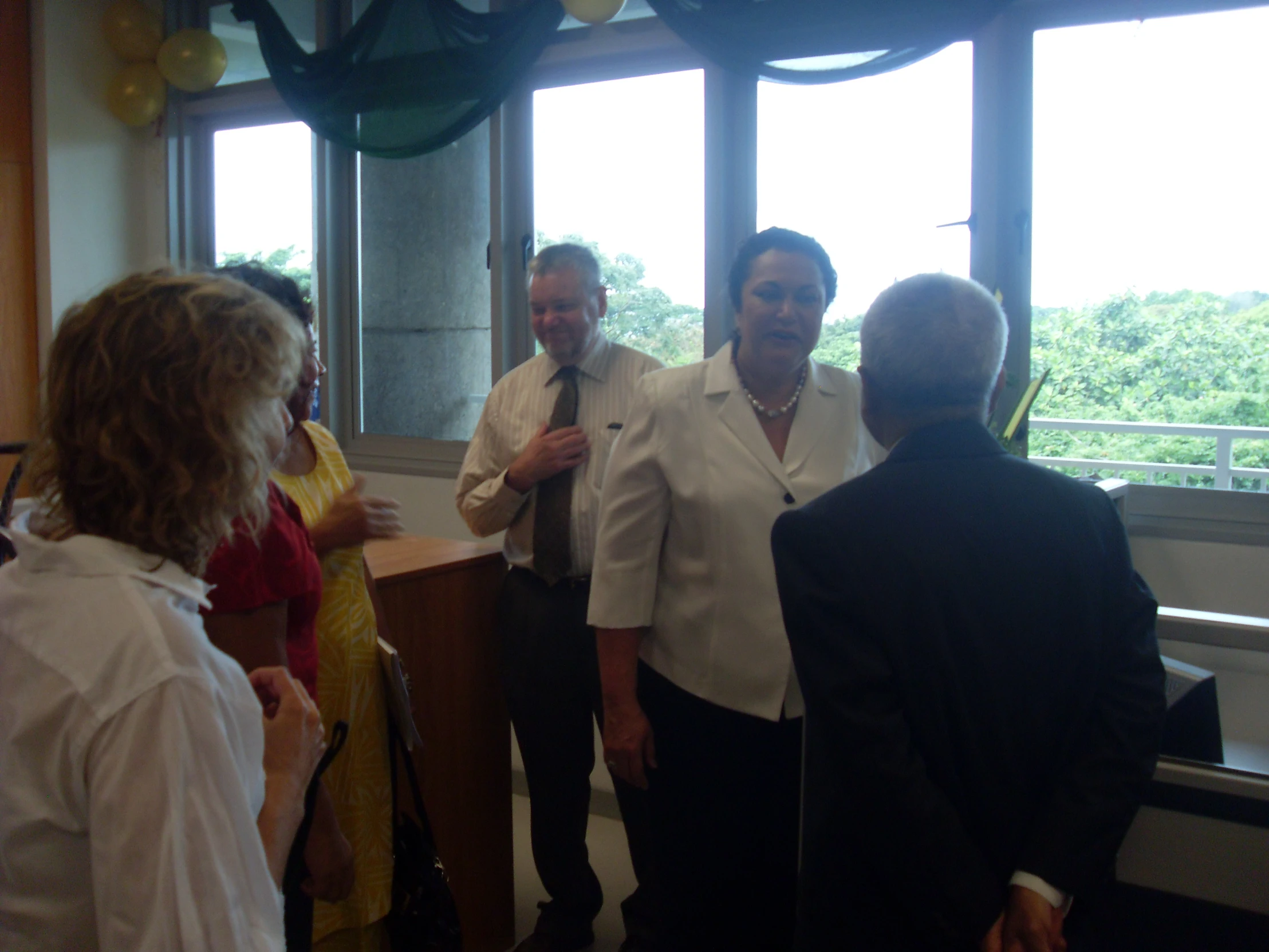 two women and a man having conversation with a woman wearing a white shirt