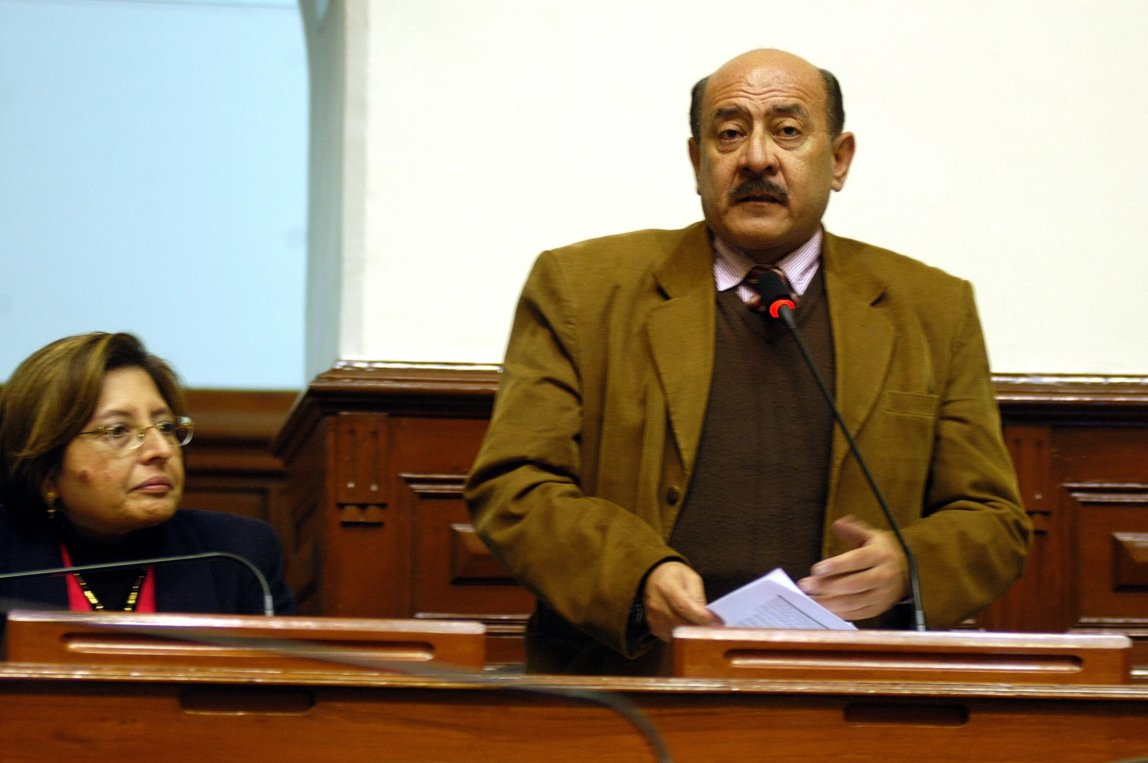 a man standing at a microphone with a lady behind him