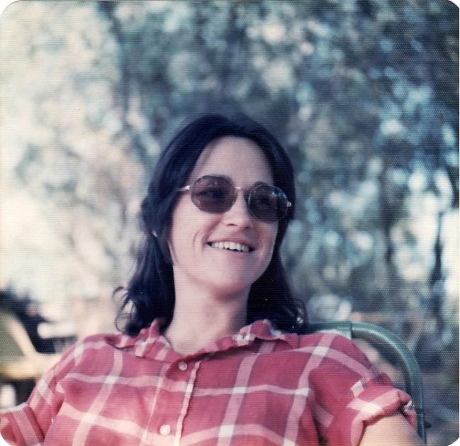 woman wearing plaid shirt and sunglasses in front of tree