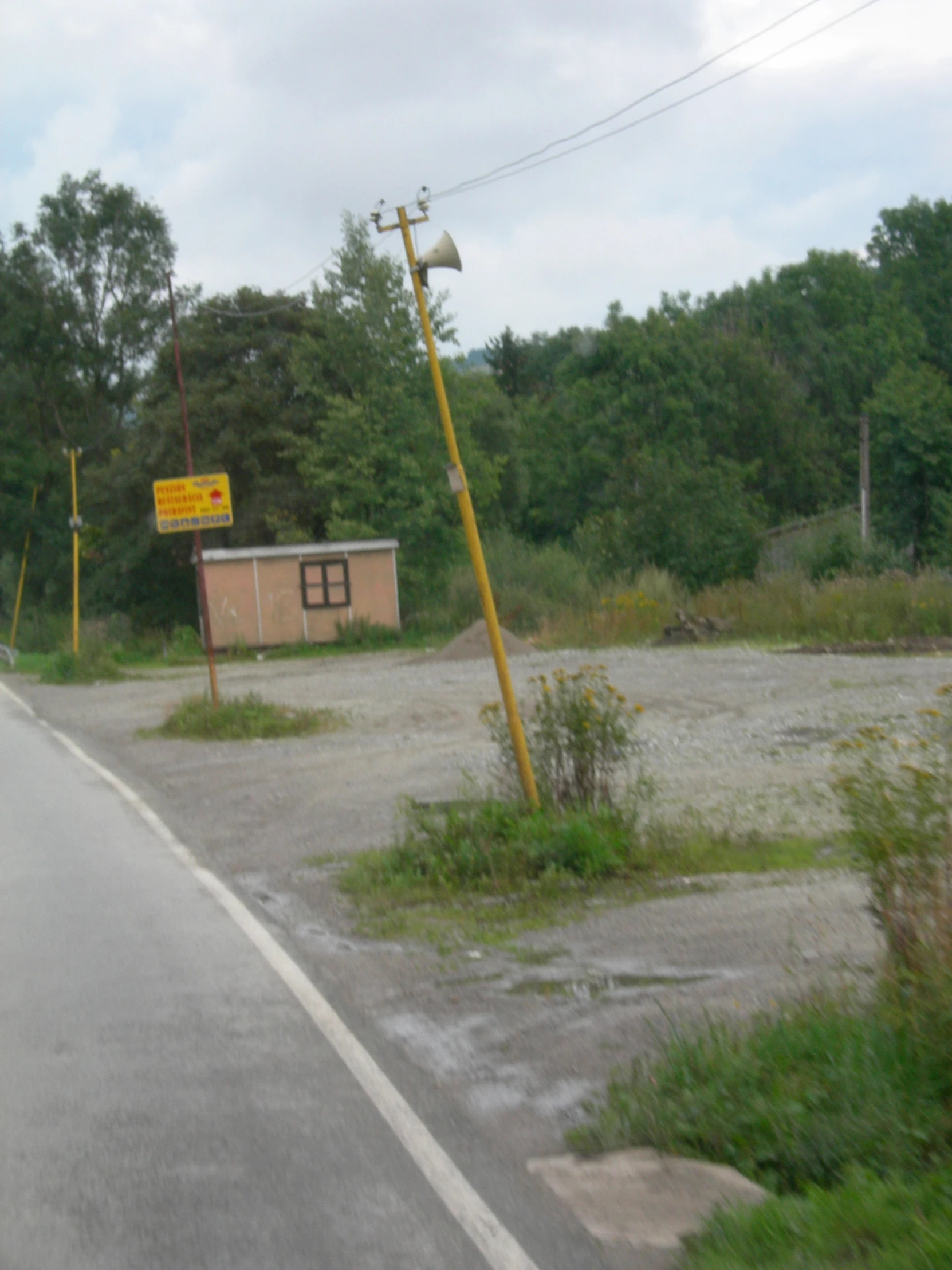 the abandoned building sits next to a dirt road