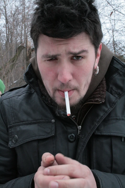 a man with a cigarette in his mouth and looking down at the ground