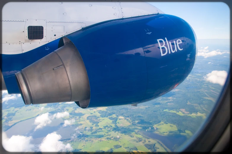 closeup of blue jet engine and wing in the sky