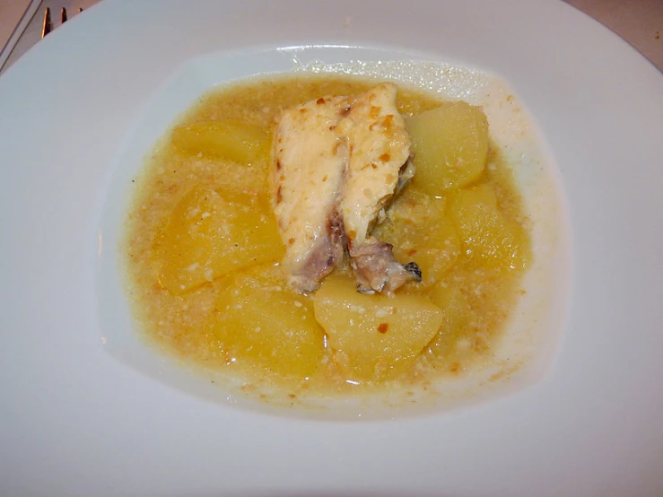 a plate with some meat and potatoes in broth