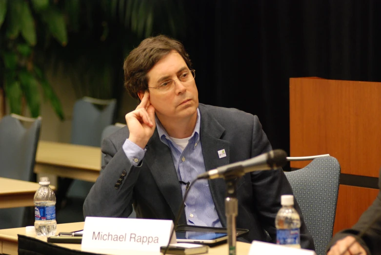 a man sitting in front of microphones at a table with a person