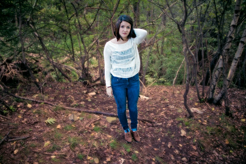 woman in white shirt and jeans standing on tree nches