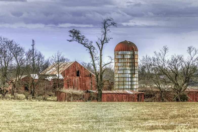 a farm with a barn and silos sitting in a field