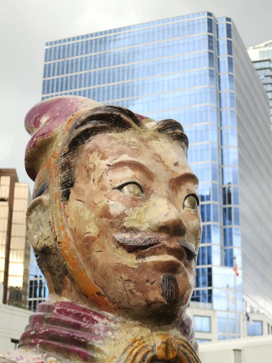 a clay bust of a man sitting in front of a tall building