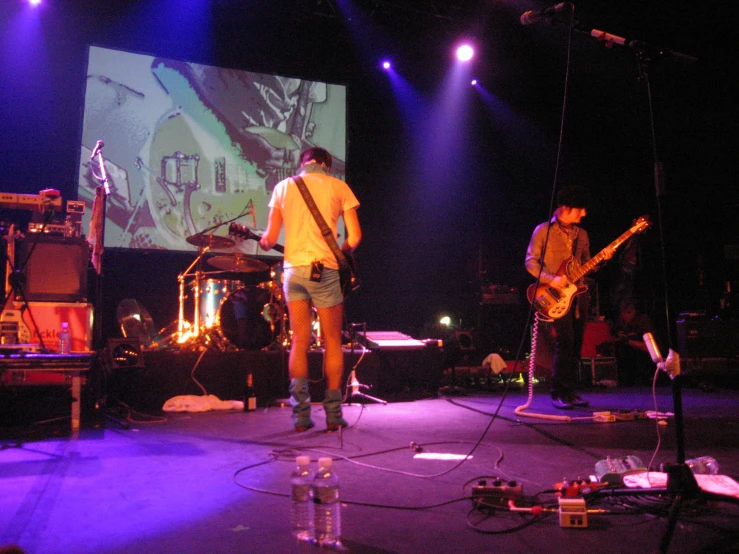 two guys playing musical on stage at night