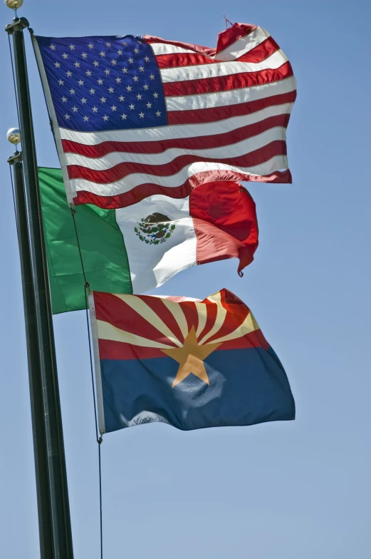 flags flying together in the wind on a clear day