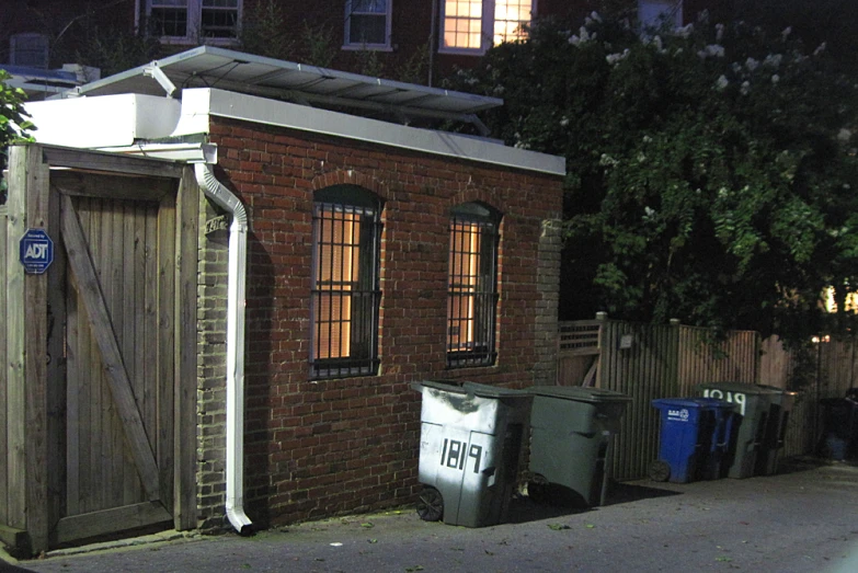 a dark, brick outhouse sits outside of a neighborhood at night