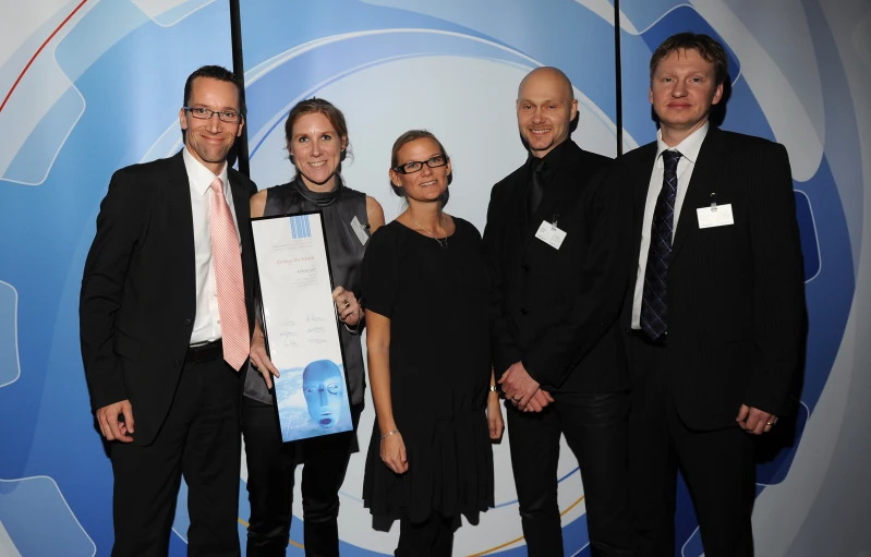 four people posing for the camera with an award