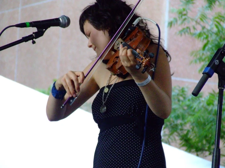 the woman is playing a violin while singing into the microphone