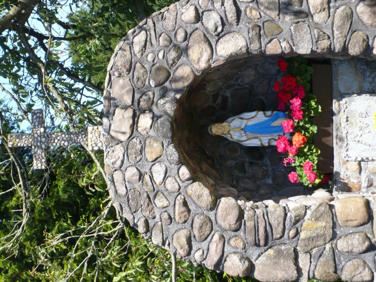 a statue surrounded by flowers sits in an arch