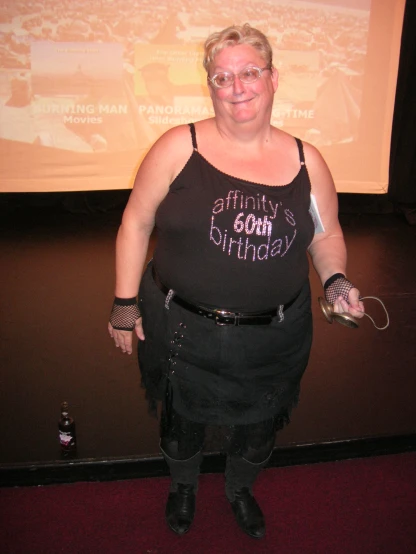 a woman wearing a  with tattoos standing in front of a large screen